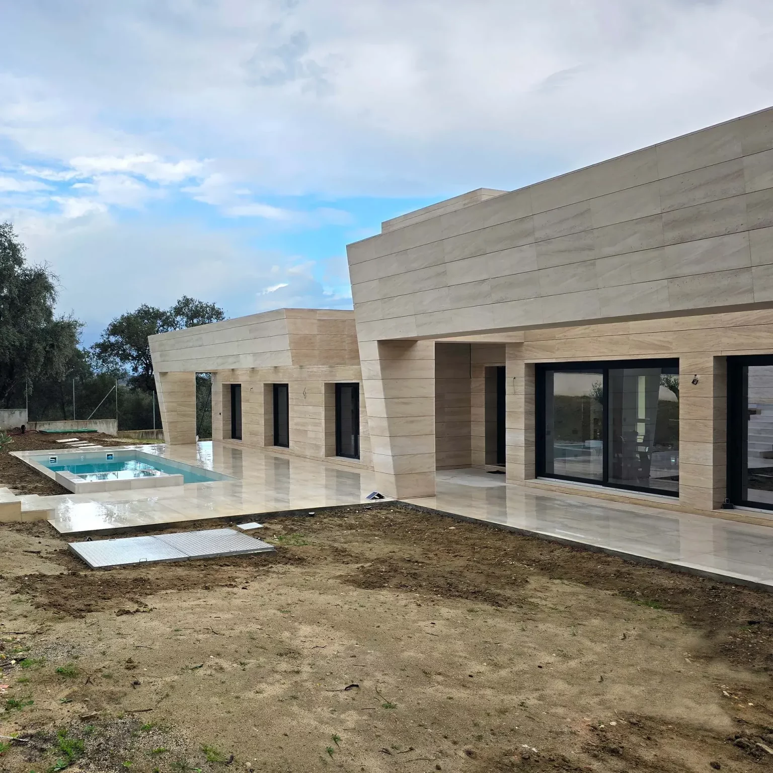 Detalle arquitectónico del revestimiento de piedra natural en un volumen cúbico moderno de Villa L26.